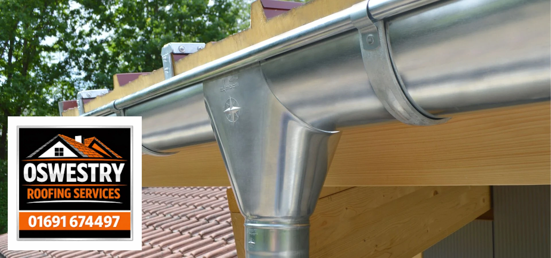 Metal gutter outlet and downpipe beside a timber fascia